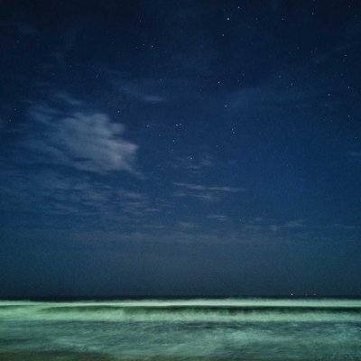 Calmed sea and starry sky, both meeting at the horizon.