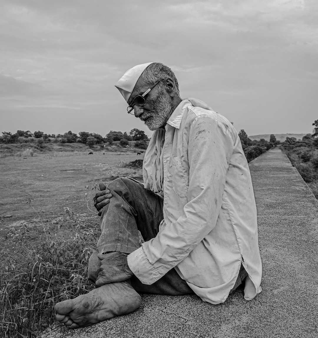 a farmer sitting peacefully near his animals.