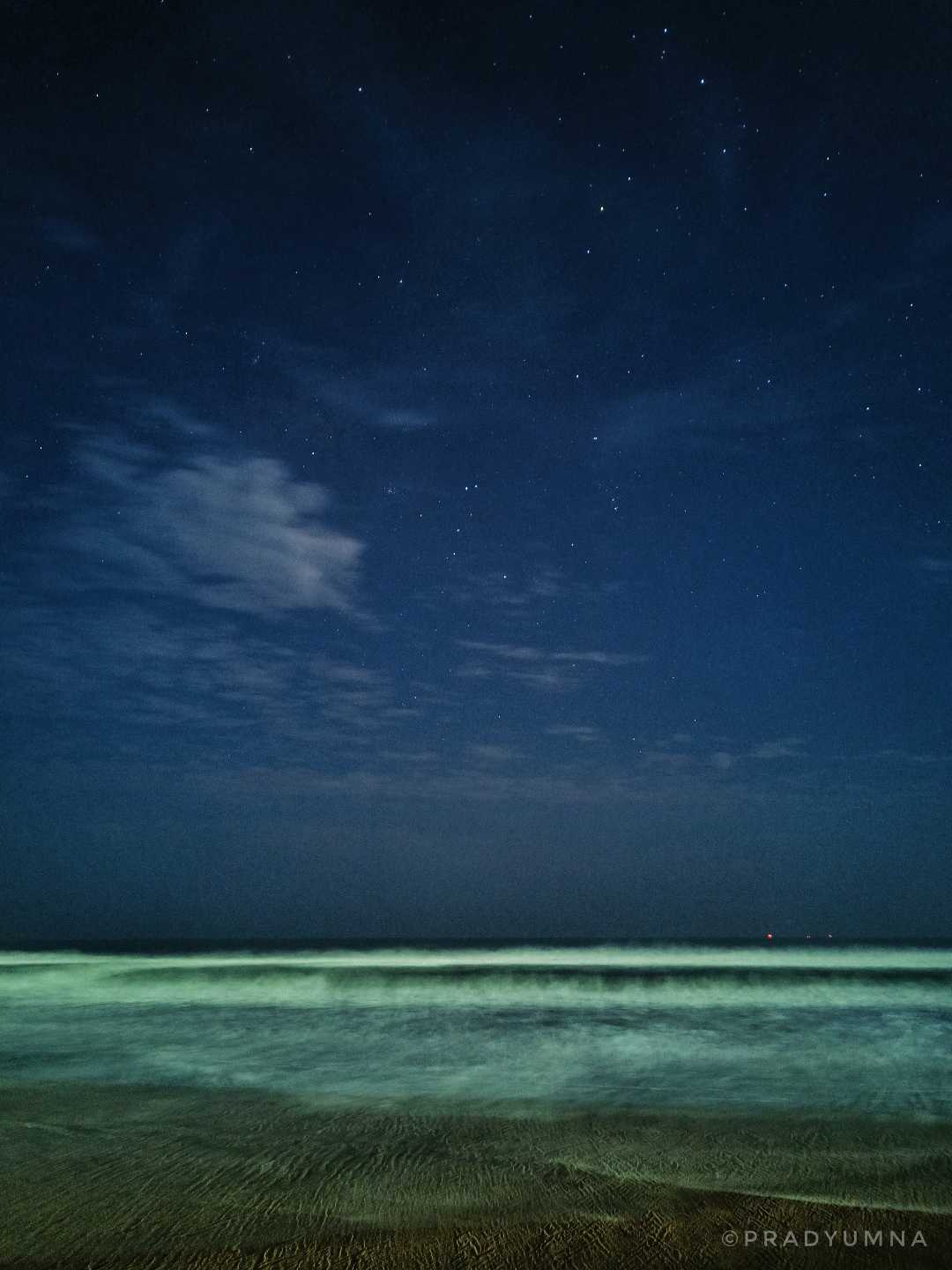 Calmed sea and starry sky, both meeting at the horizon.